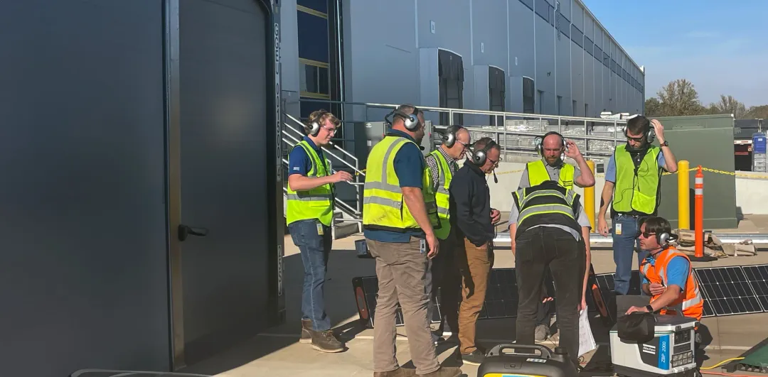 New hires in safety vests wearing headsets outside a facility