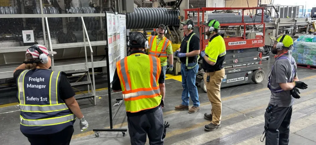 Team in safety vests wearing headsets on a GEMBA walk