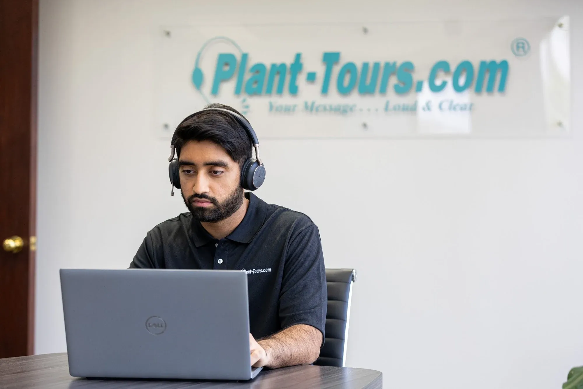Plant-Tours.com team member wearing a headset at a laptop in the office