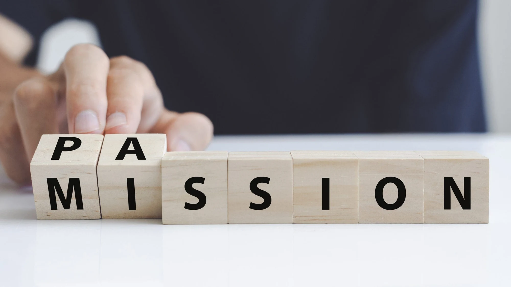 Hand turning wooden blocks to change the word mission into passion