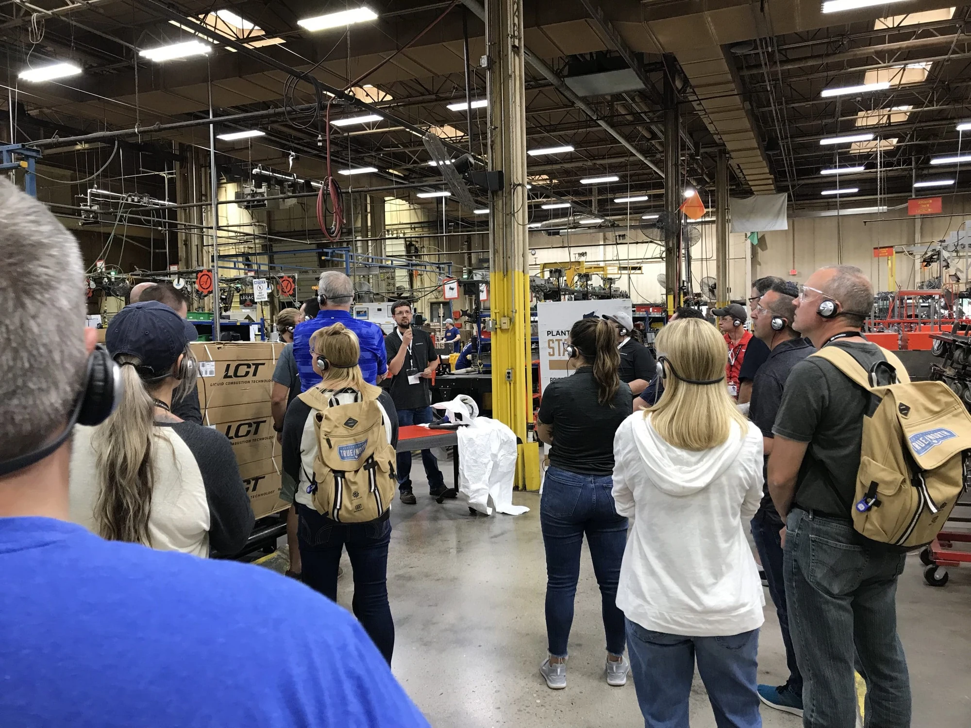 Large group of visitors touring a busy factory floor
