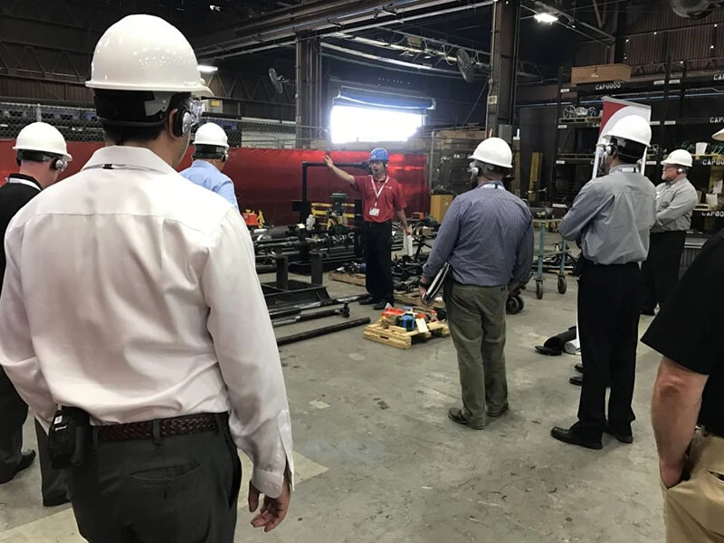 Visitors in white hard hats on a tour of a manufacturing facility